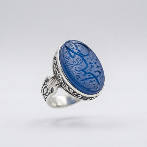 Blauer Jemen Aqīq Siegelring «Siegelschrift» aus massivem 925 Feinsilber, schwebend in 3/4-Seitenansicht mit detailreichen, historischen Gravuren auf dem ovalen Stein, auf hellgrauem Studio-Hintergrund.
